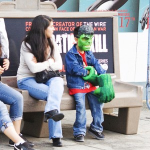 En liten Hulk, en liten hjälte, sitter på en bänk.